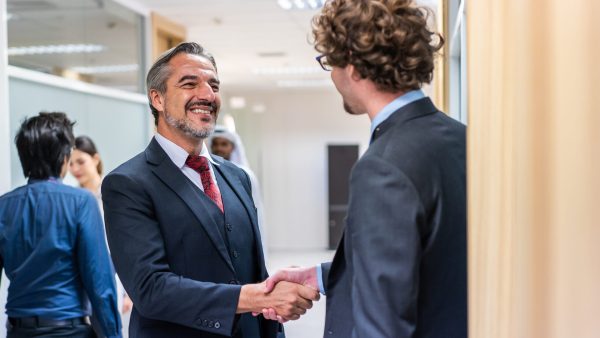 caucasian-businessman-making-a-handshake-together-2025-03-31-07-35-11-utc Caucasian businessman making a handshake together while stand in office. Attractive team of employee worker enjoy partnership agreement after negotiations for business deal during working in corporate