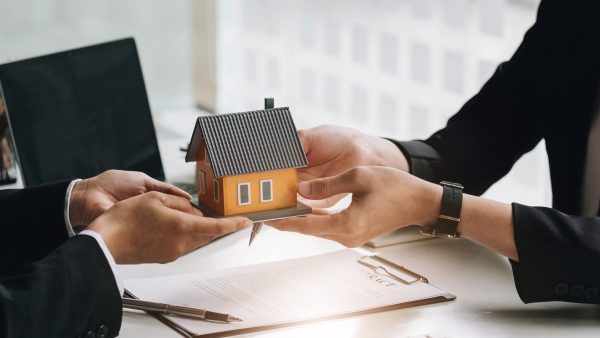 Real estate broker agent presenting and consult to customer to decision making sign insurance form agreement, home model, concerning mortgage loan offer for and house insurance.